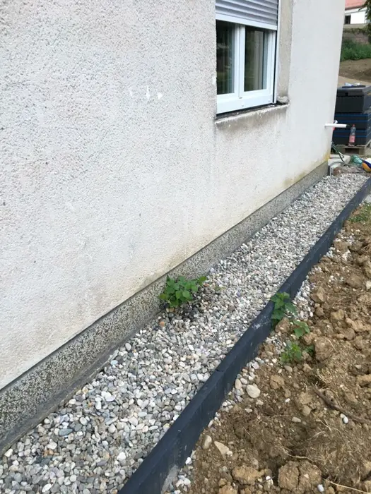 Crni ivičnjak uz kuću sa dekorativnim kamenom