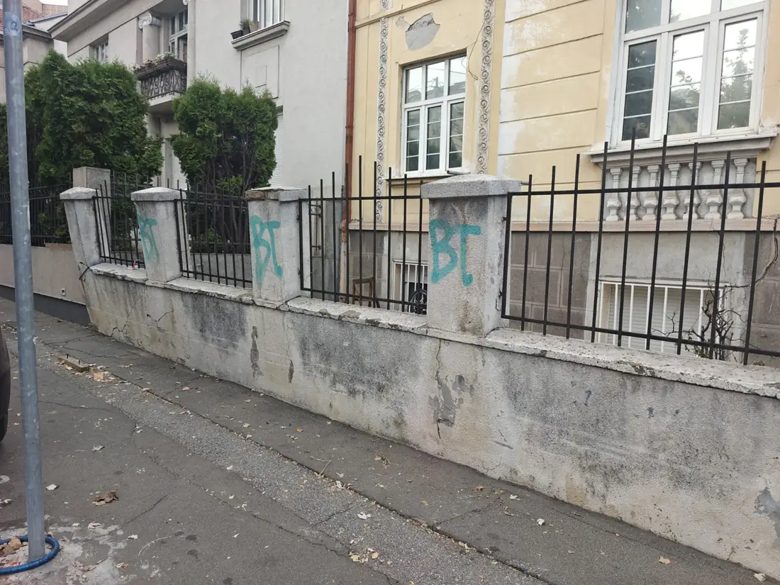 Stara zidana ograda sa betonskim stubovima i metalnim šipkama pre rušenja