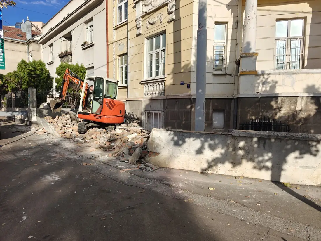 Mini-bager i srušeni delovi zidane ograde ispred objekta